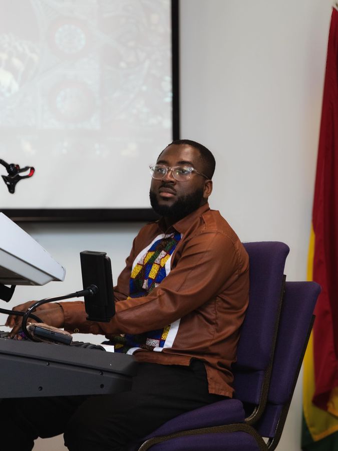 Keyboardist leading worship beside the Ghana flag